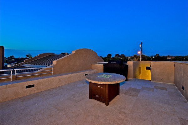 A rooftop deck with a fire pit and a grill