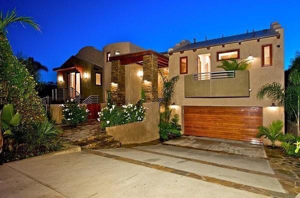 A large house with a wooden garage door is lit up at night