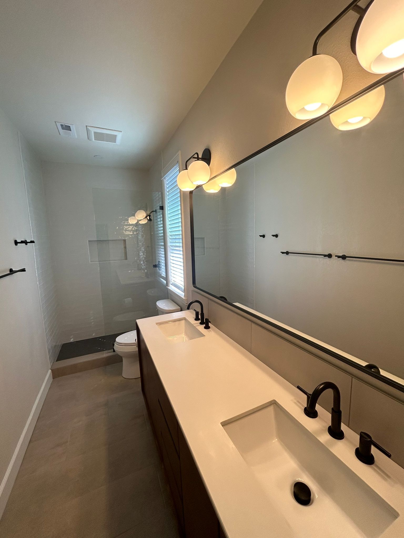 A bathroom with two sinks , a toilet , and a large mirror.