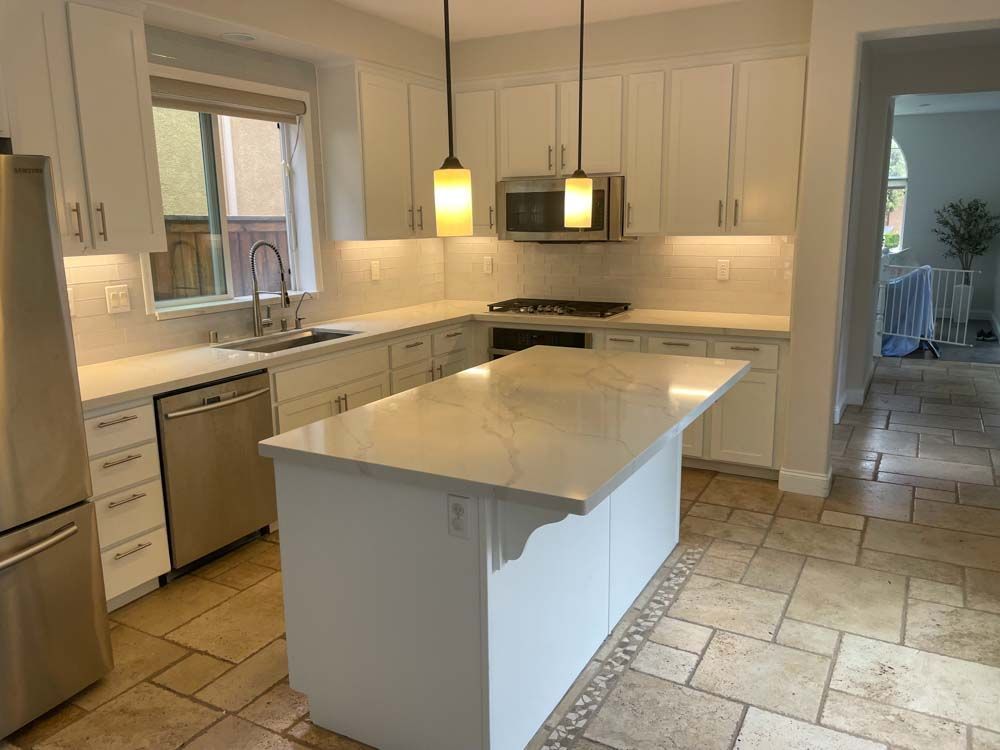 A kitchen in San Marcos, CA with white cabinets , stainless steel appliances , and a large island.