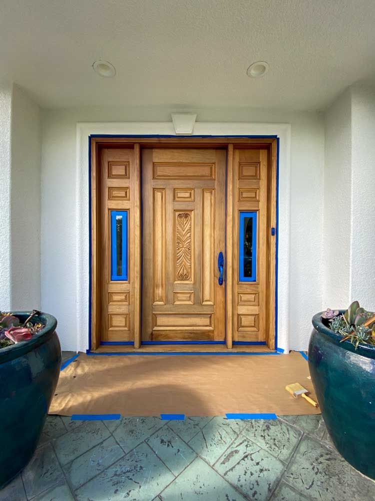 A large wooden door is being painted in a house.