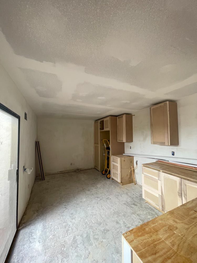 A kitchen under renovation construction with wooden cabinets and a concrete floor.