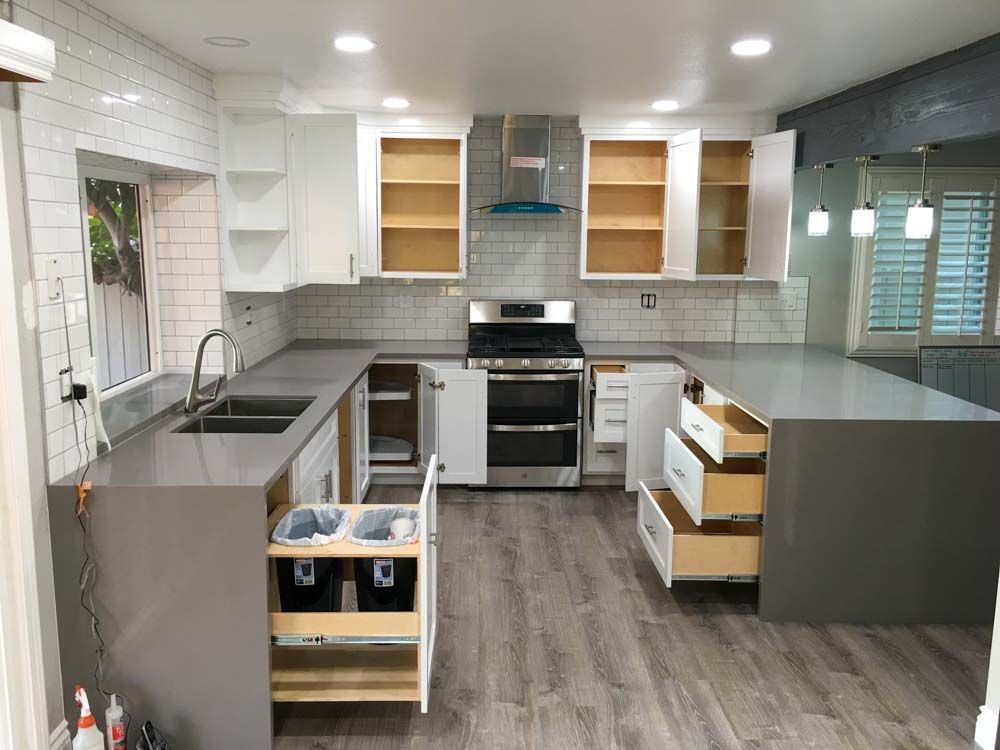 A kitchen with a stove, sink , and drawers open.