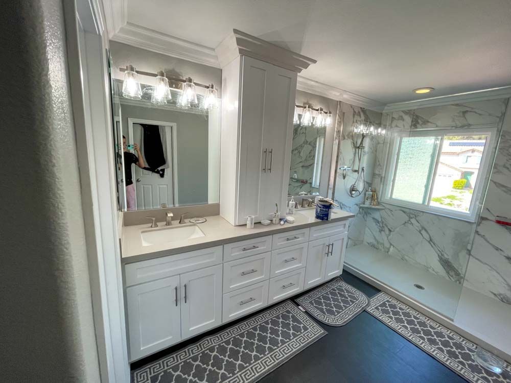 A bathroom with two sinks, two mirrors and a walk in shower.