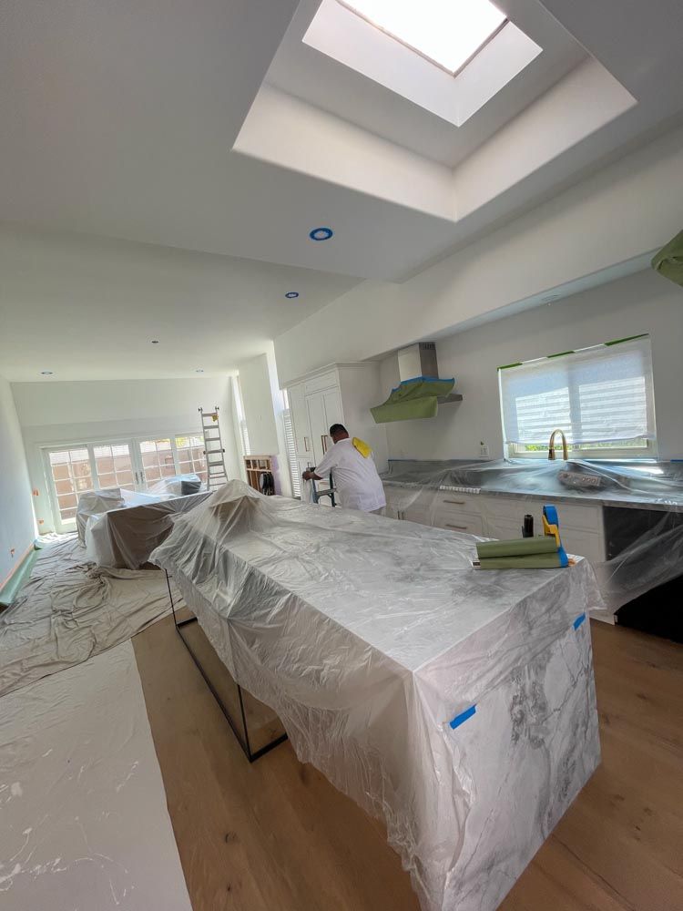 A man is painting a kitchen with a skylight.