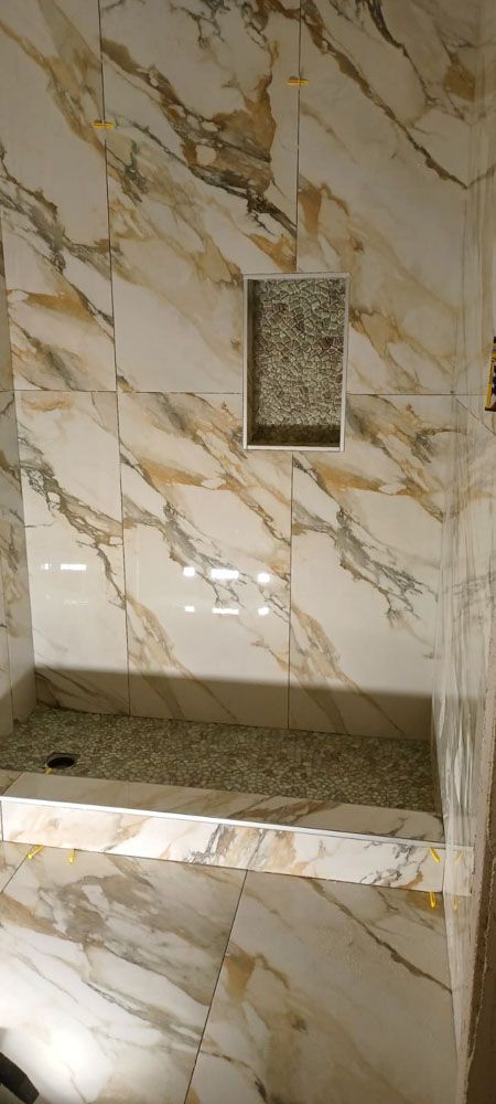 A bathroom with marble tiles and a walk in shower.