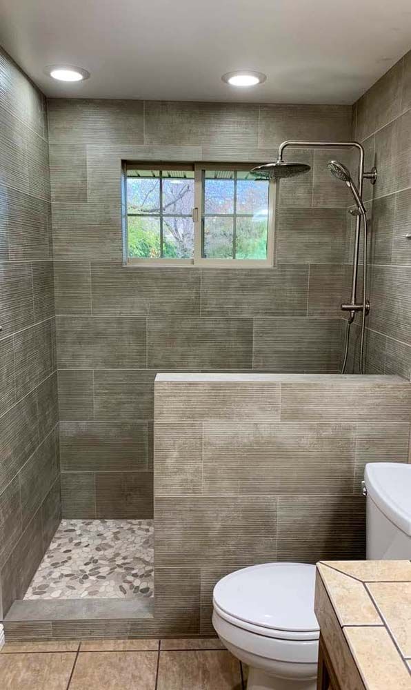 A bathroom with a toilet, shower, and window.