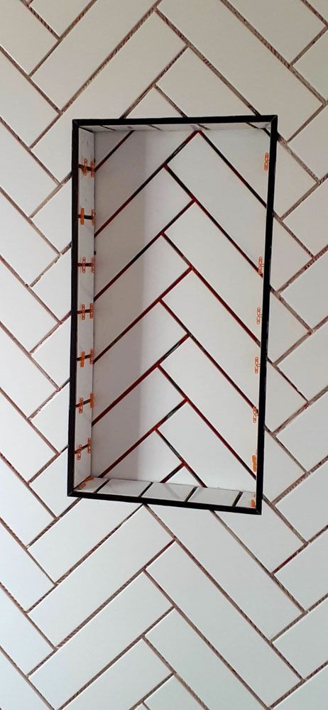 A picture frame is hanging on a wall with a herringbone pattern.