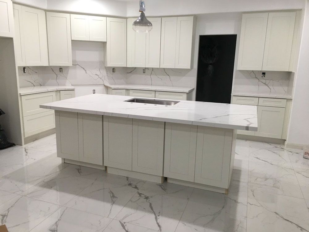 A kitchen with white cabinets and a large island in the middle.