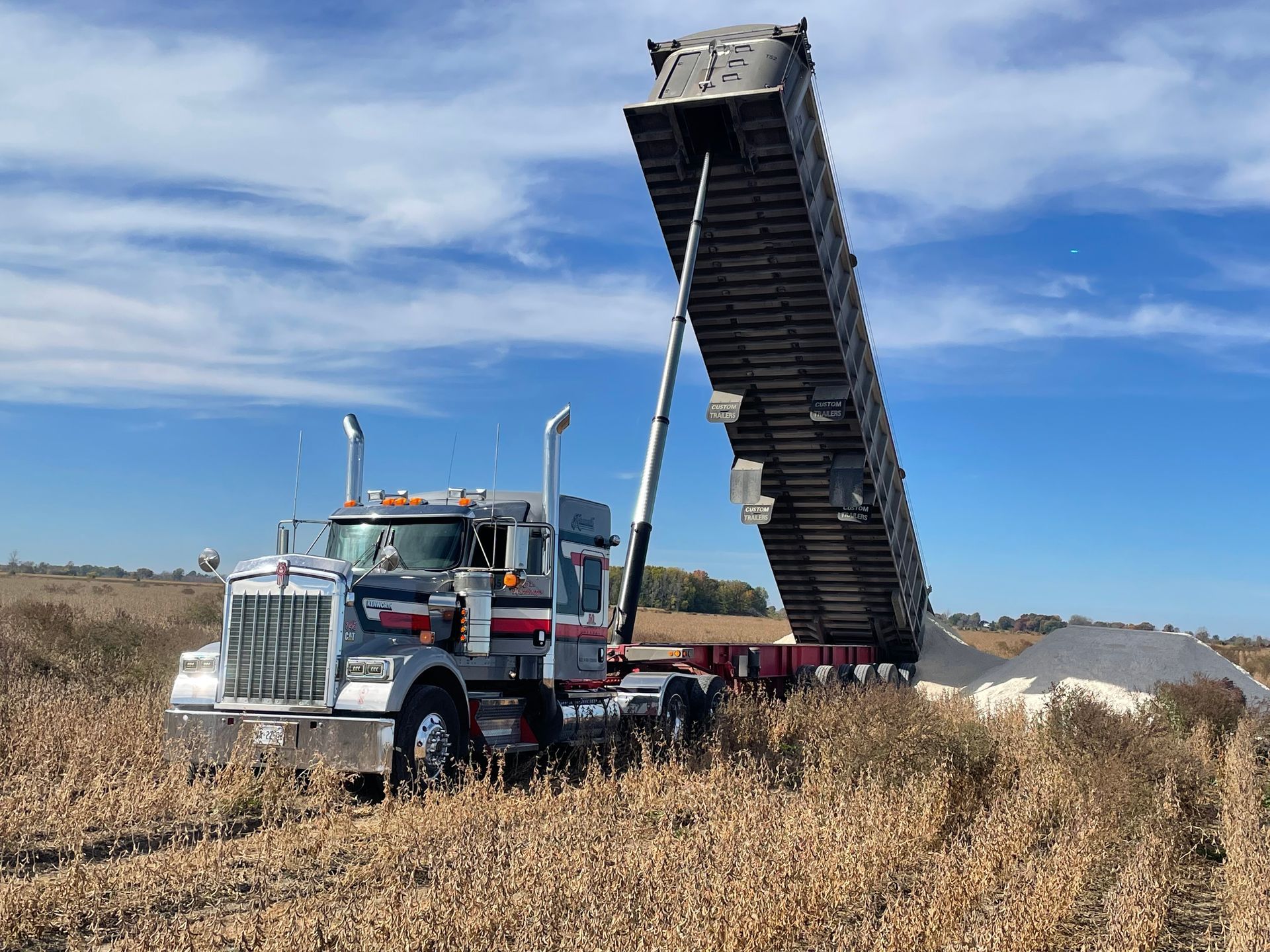 A white dump truck is driving down a highway.