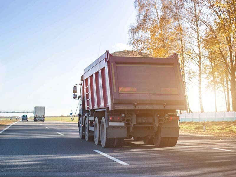 A dump truck is driving down a highway.