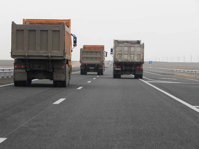 Three dump trucks are driving down a highway.