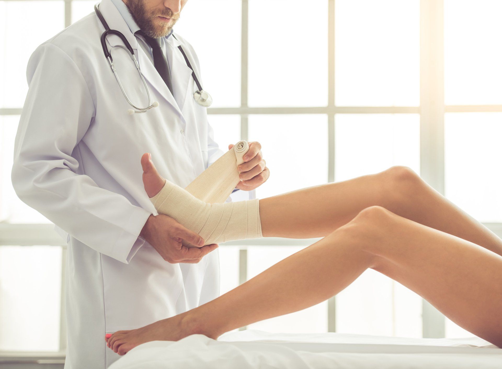 Wellness — Doctor Bandaging Woman's Injured Leg in Lancaster & Mechanicsburg, PA