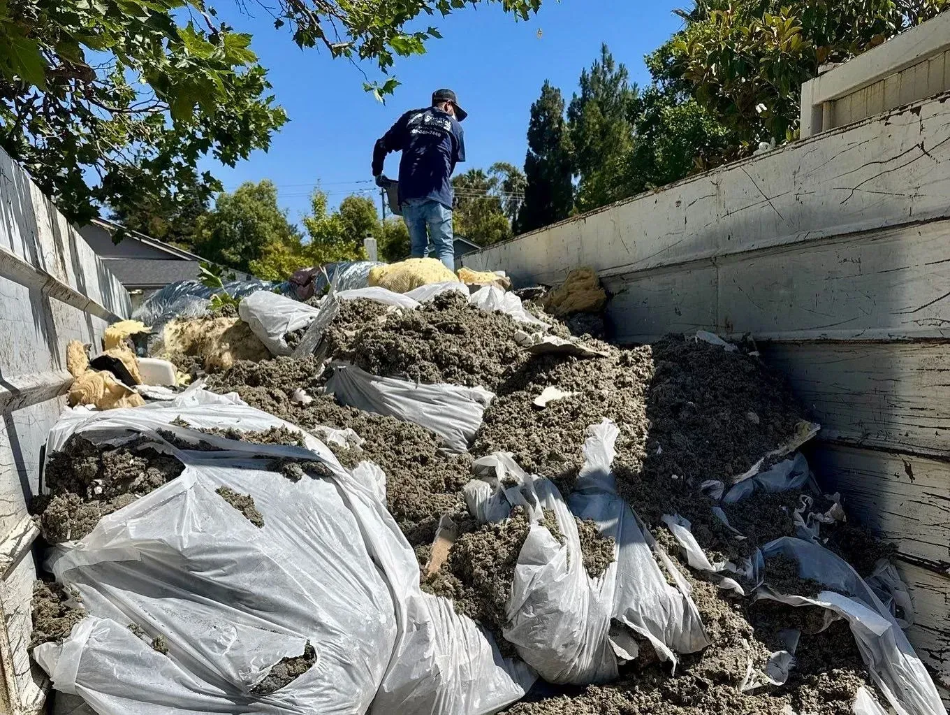 Person standing on a large pile of debris in a concrete channel under a blue sky