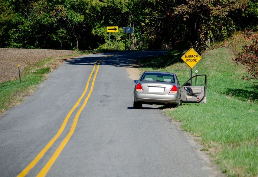 Car pulled over on a rural road with an open door, yellow taxi sign, and arrow sign.