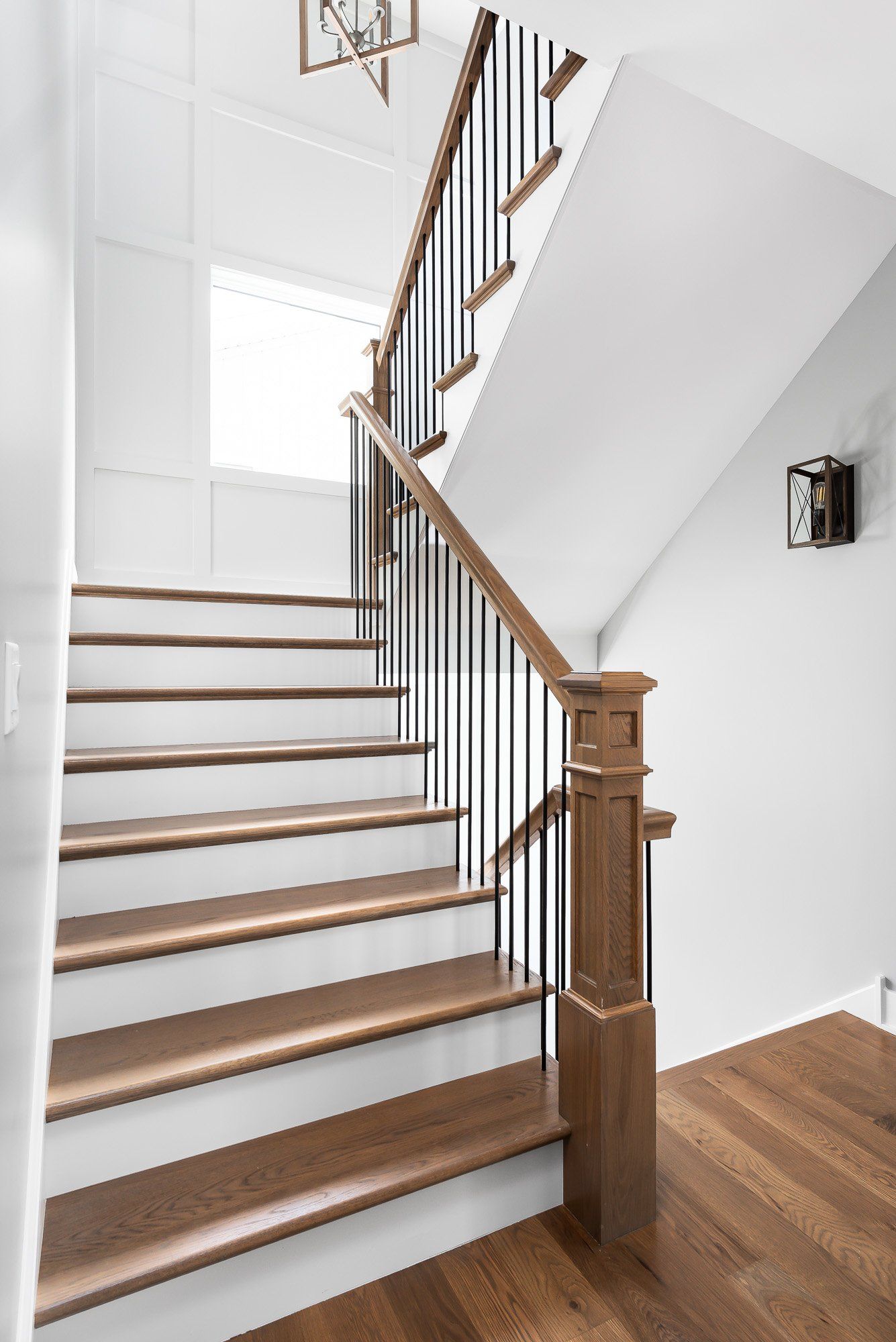 A wooden staircase with white steps and a black railing in a house.