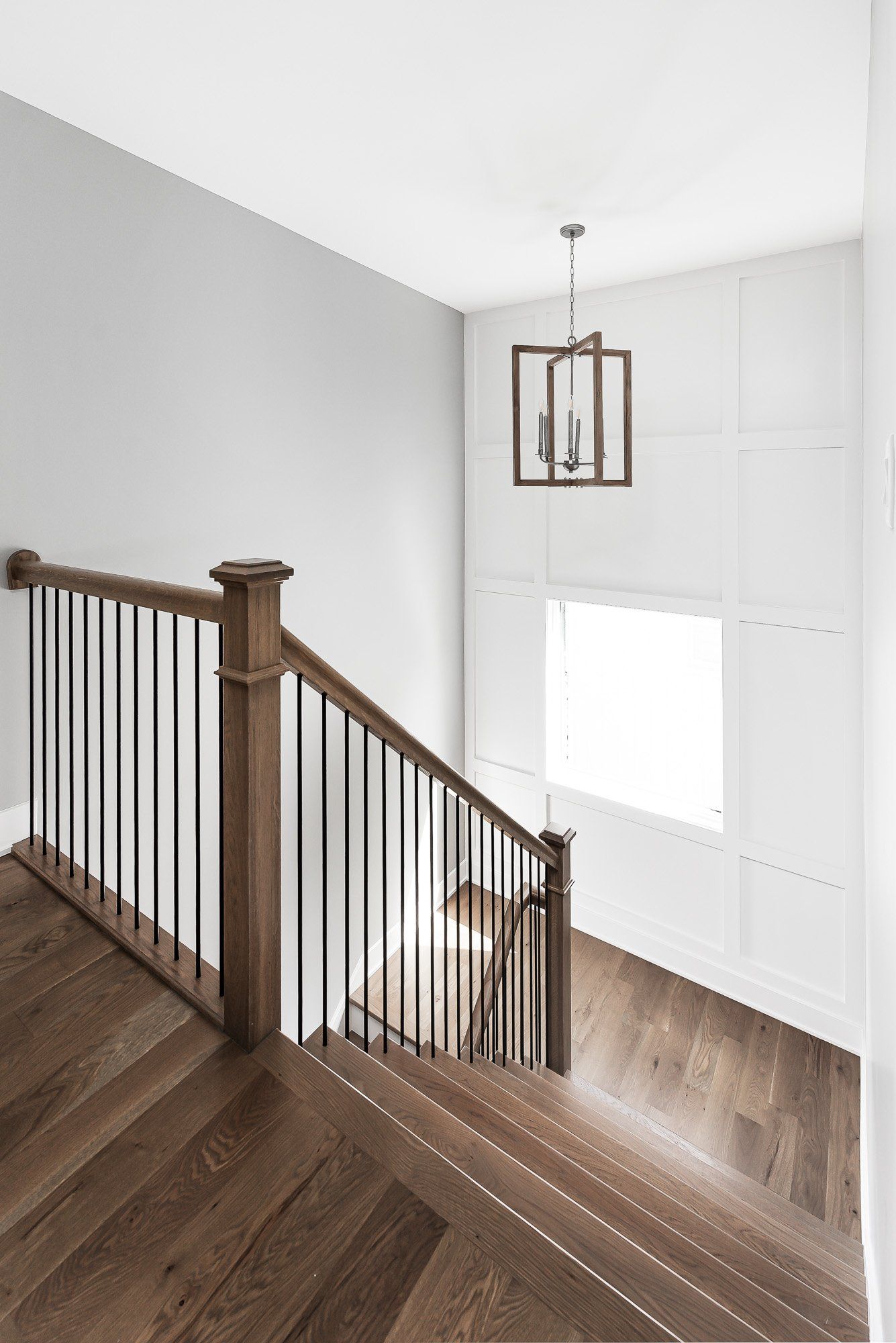A wooden staircase with a black railing and a window.