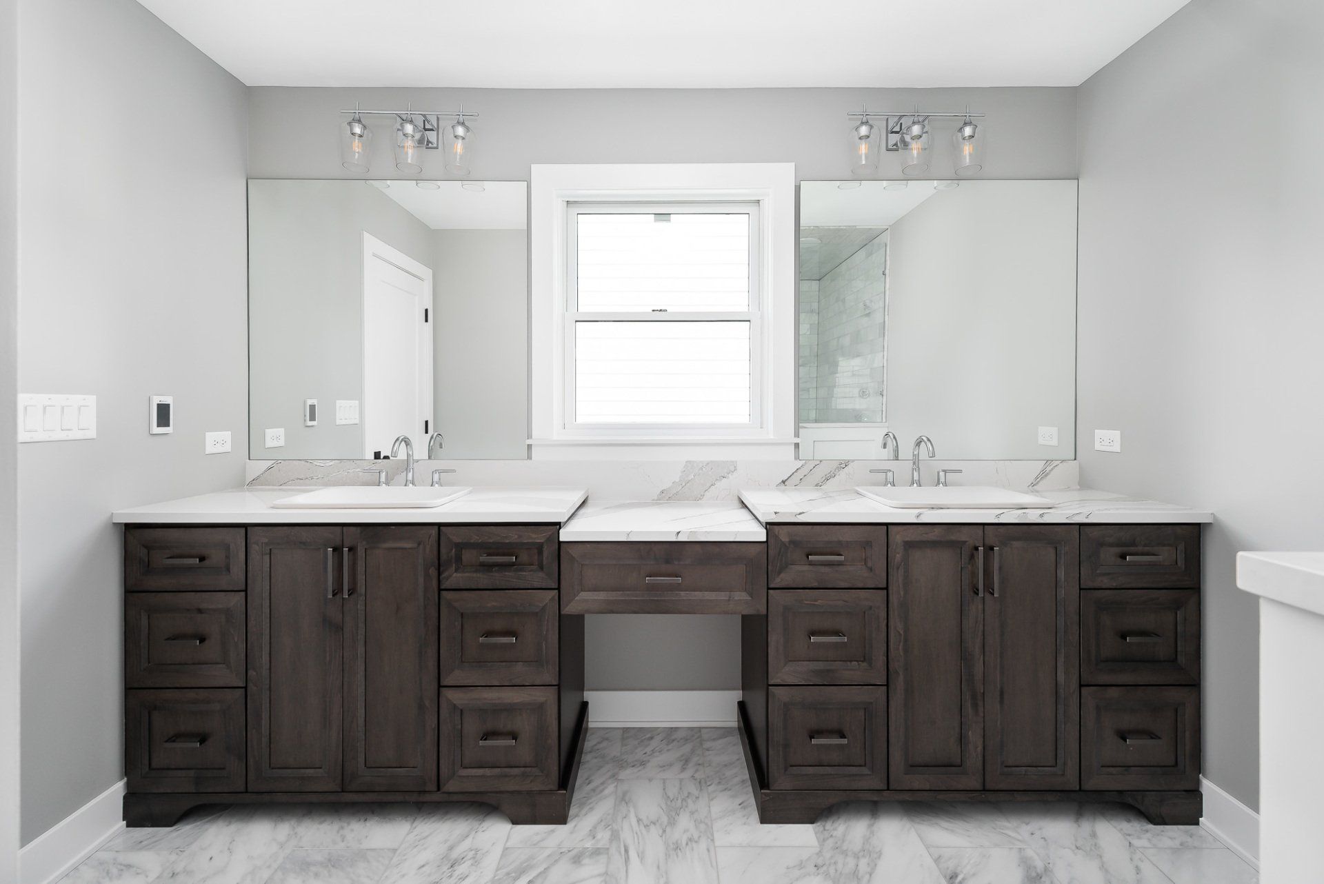 A bathroom with two sinks , two mirrors and a window.