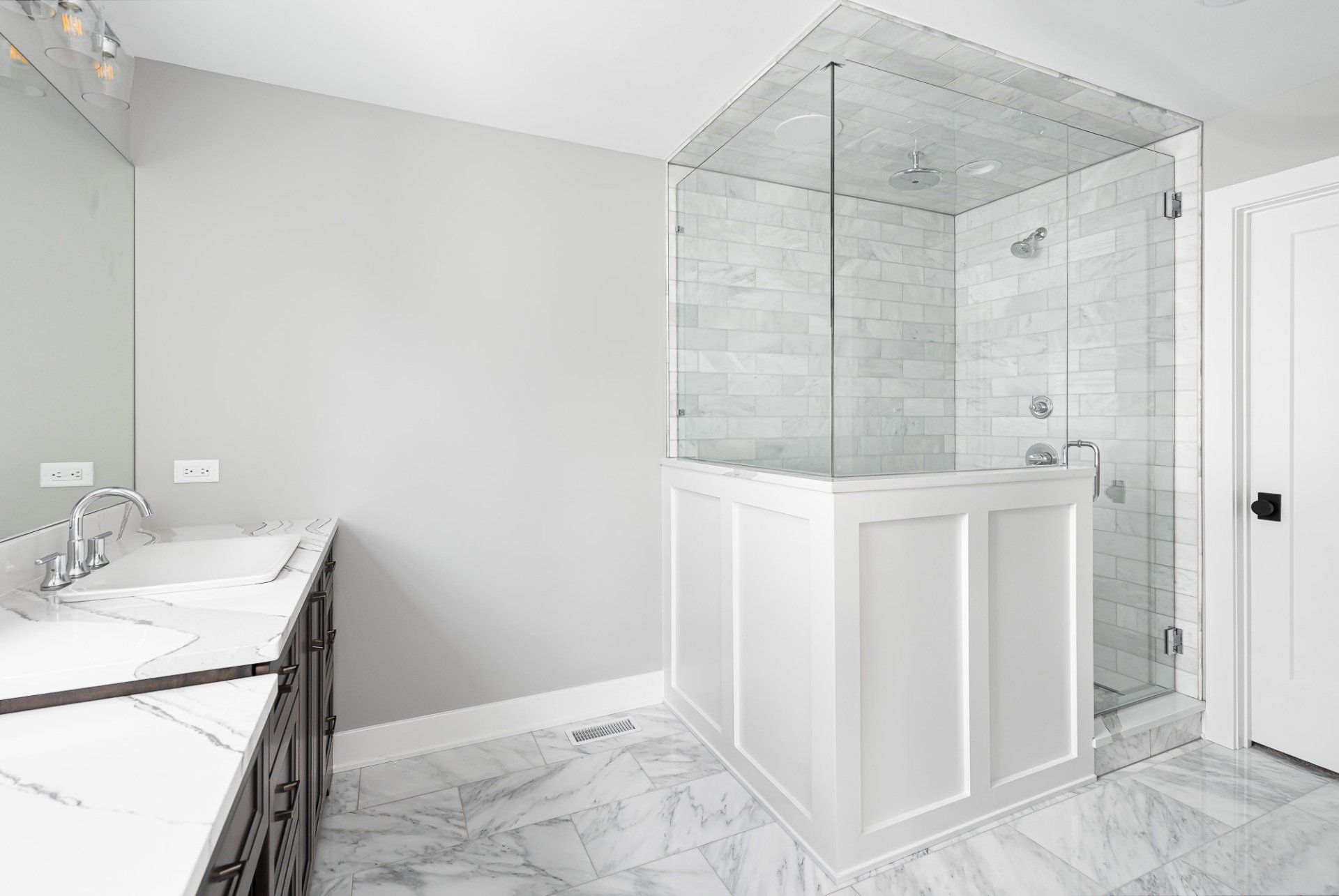 A bathroom with two sinks and a walk in shower.