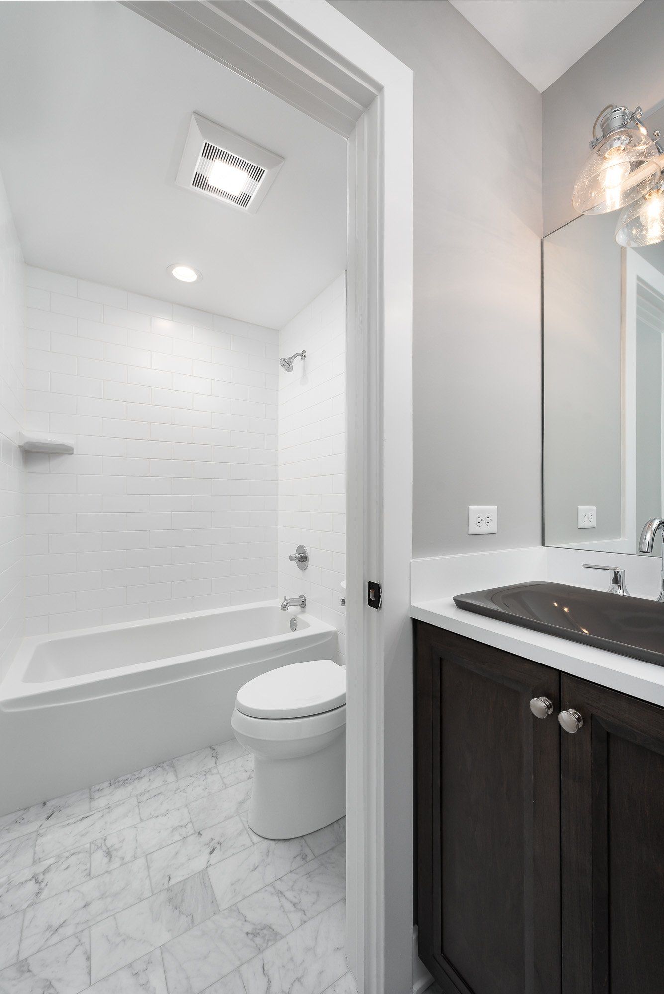 A bathroom with a toilet , sink , bathtub and mirror.