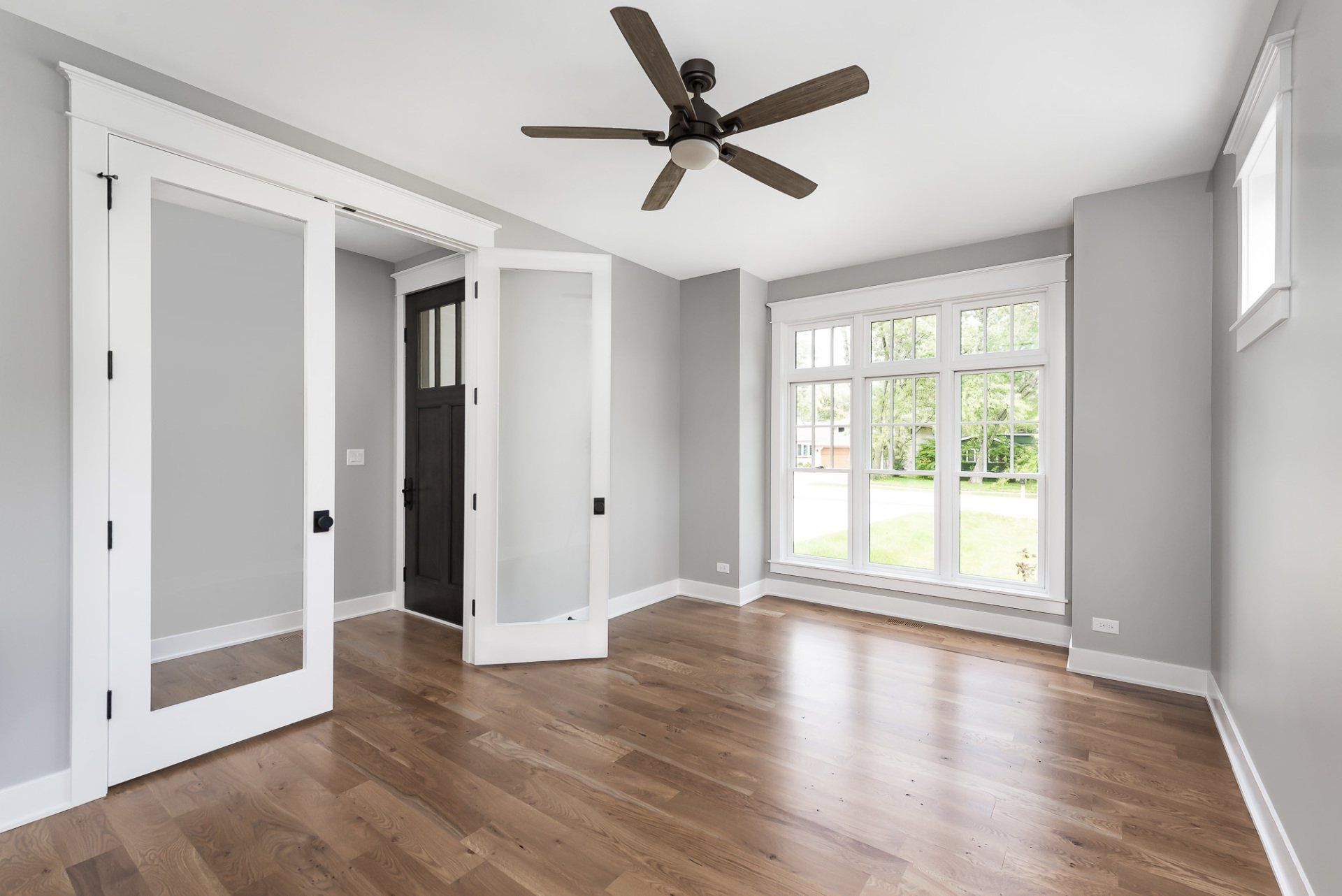 An empty living room with hardwood floors and a ceiling fan.