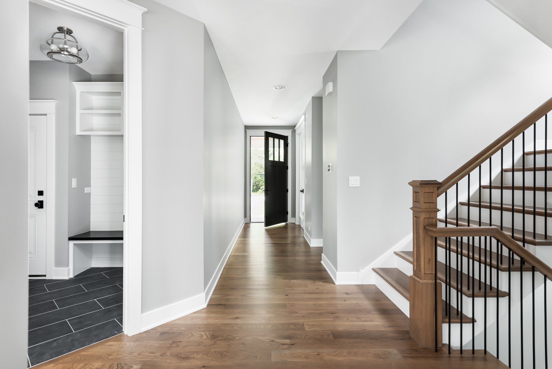 A hallway with wooden floors and stairs in a house.