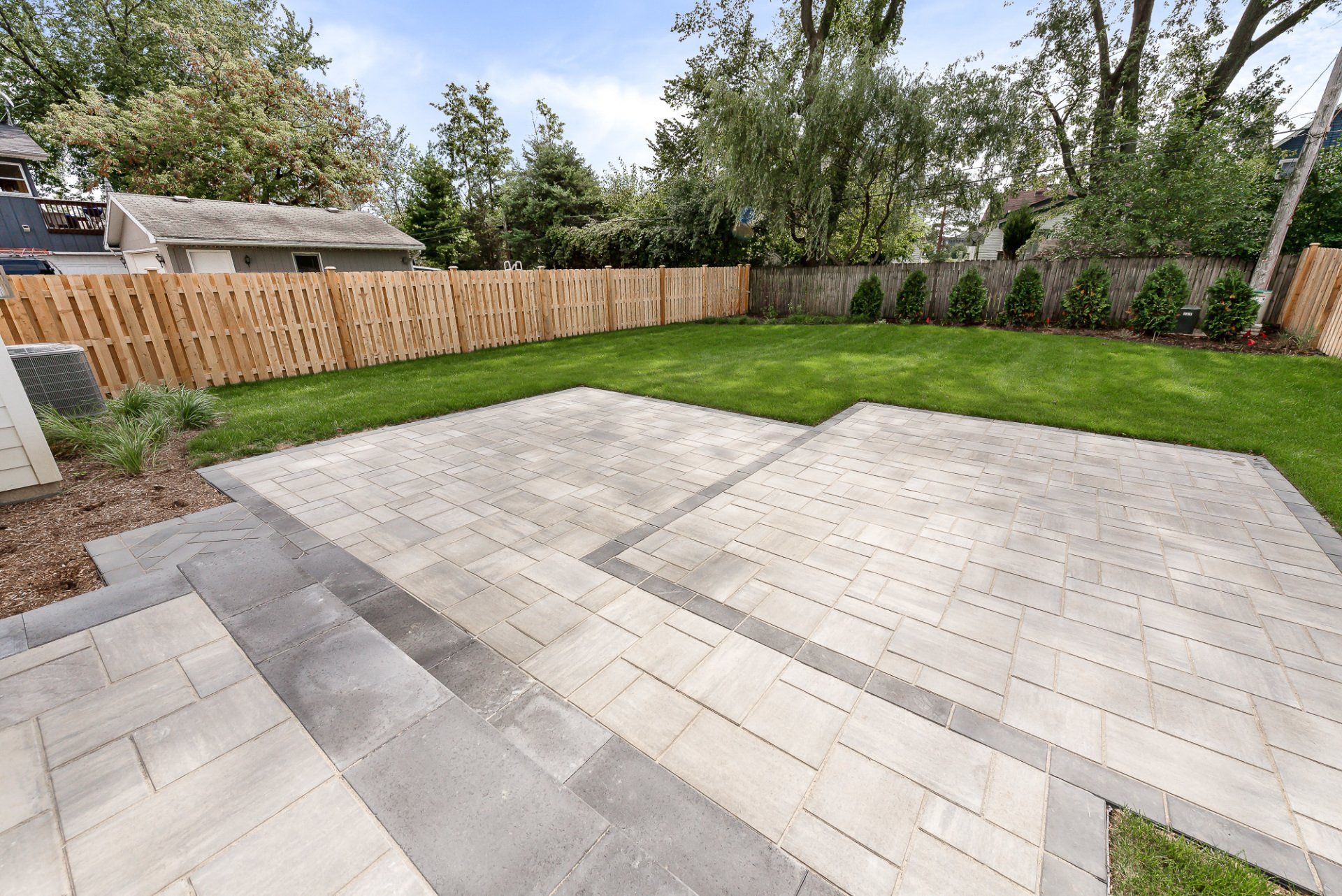 A backyard with a patio and a wooden fence