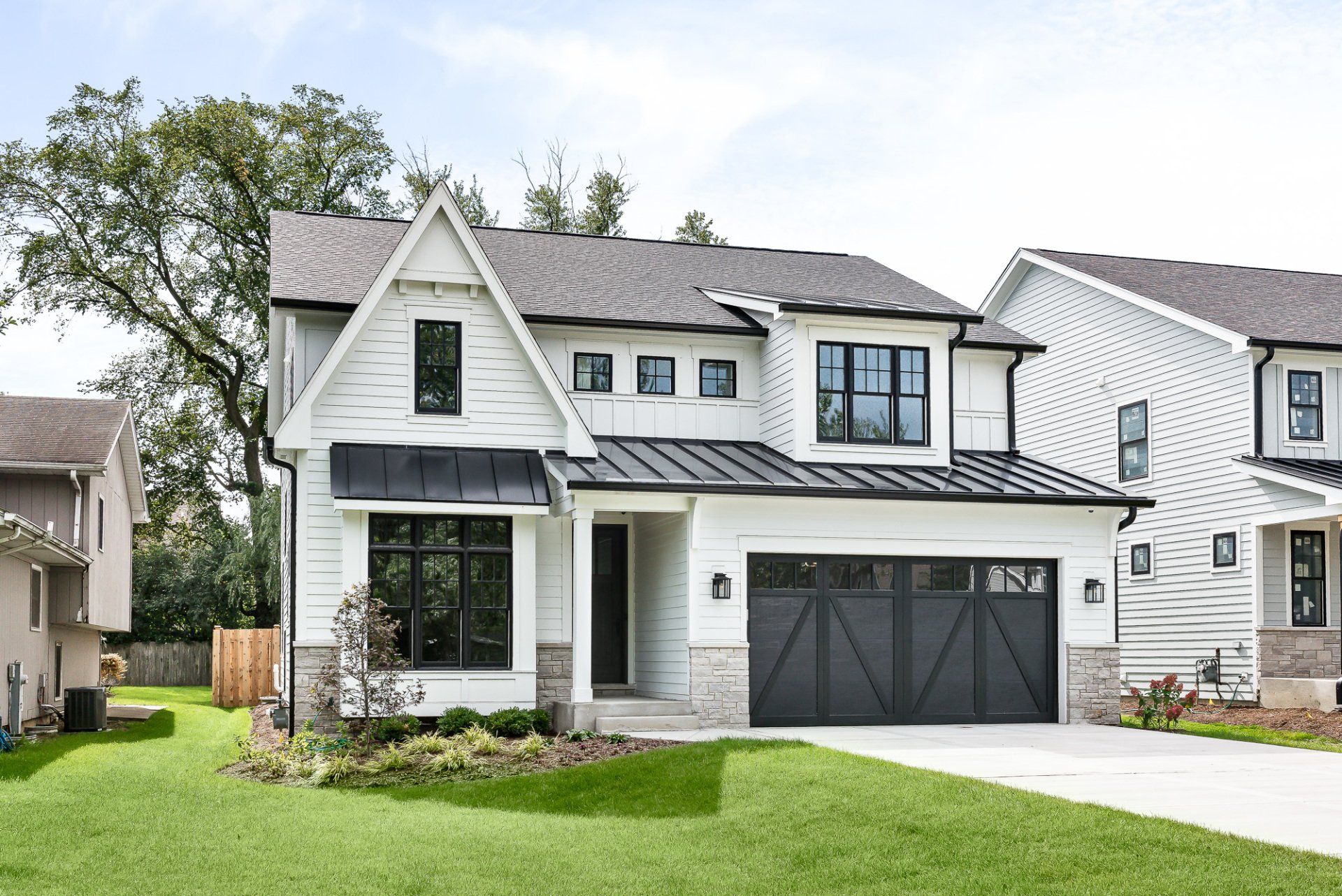 A white house with a black garage door is sitting on top of a lush green lawn.