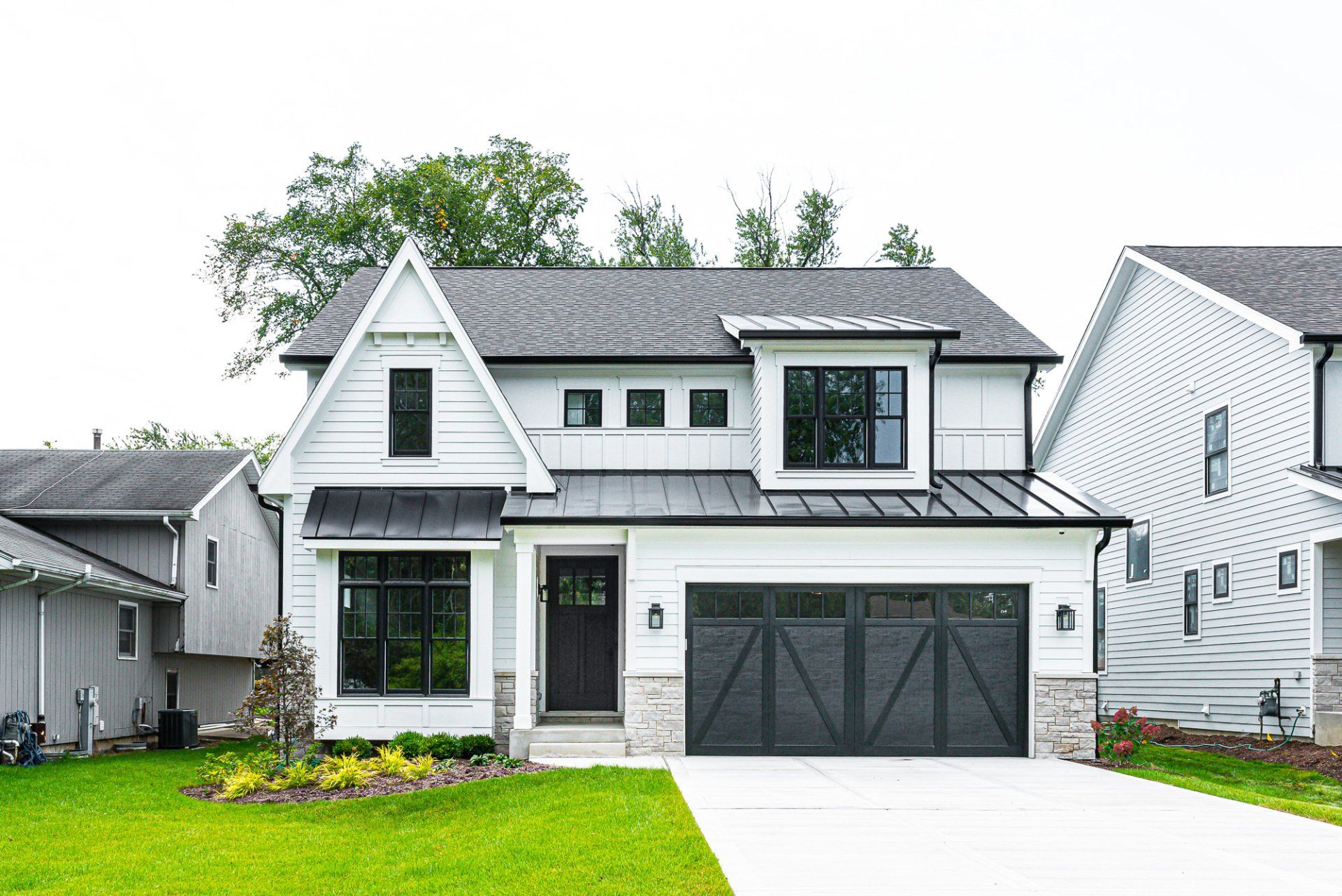 A white house with a black garage door is sitting on top of a lush green lawn.