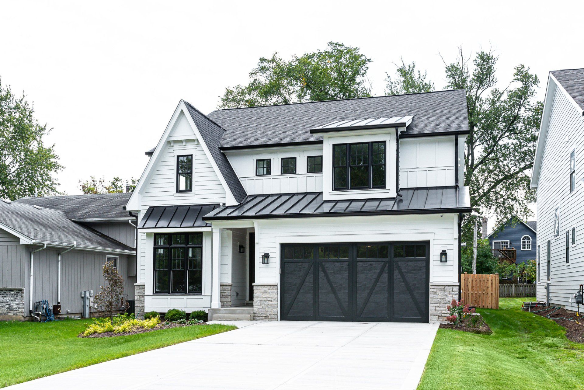 A white house with a black garage door and a gray roof.