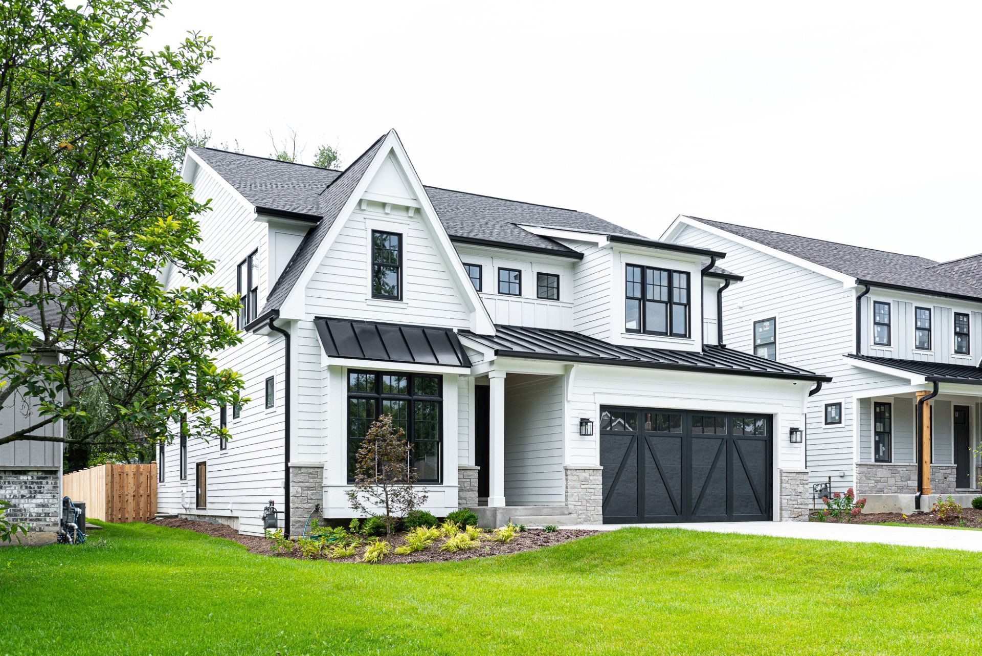 A large white house with a black garage door is sitting on top of a lush green lawn.