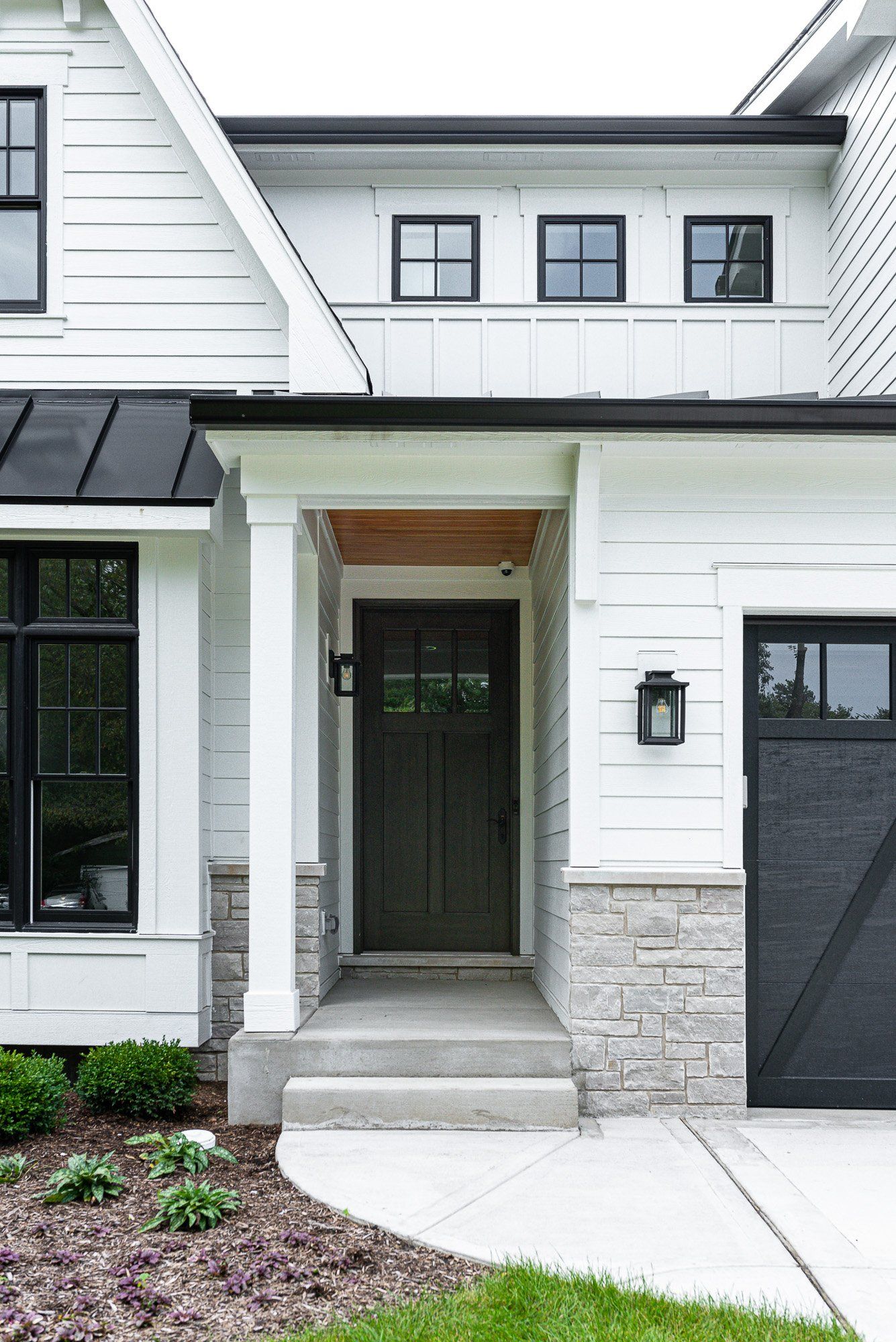A white house with a black garage door and black windows