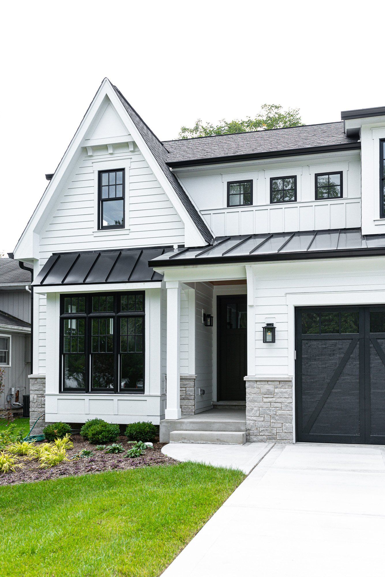 A white house with black windows and a black garage door.