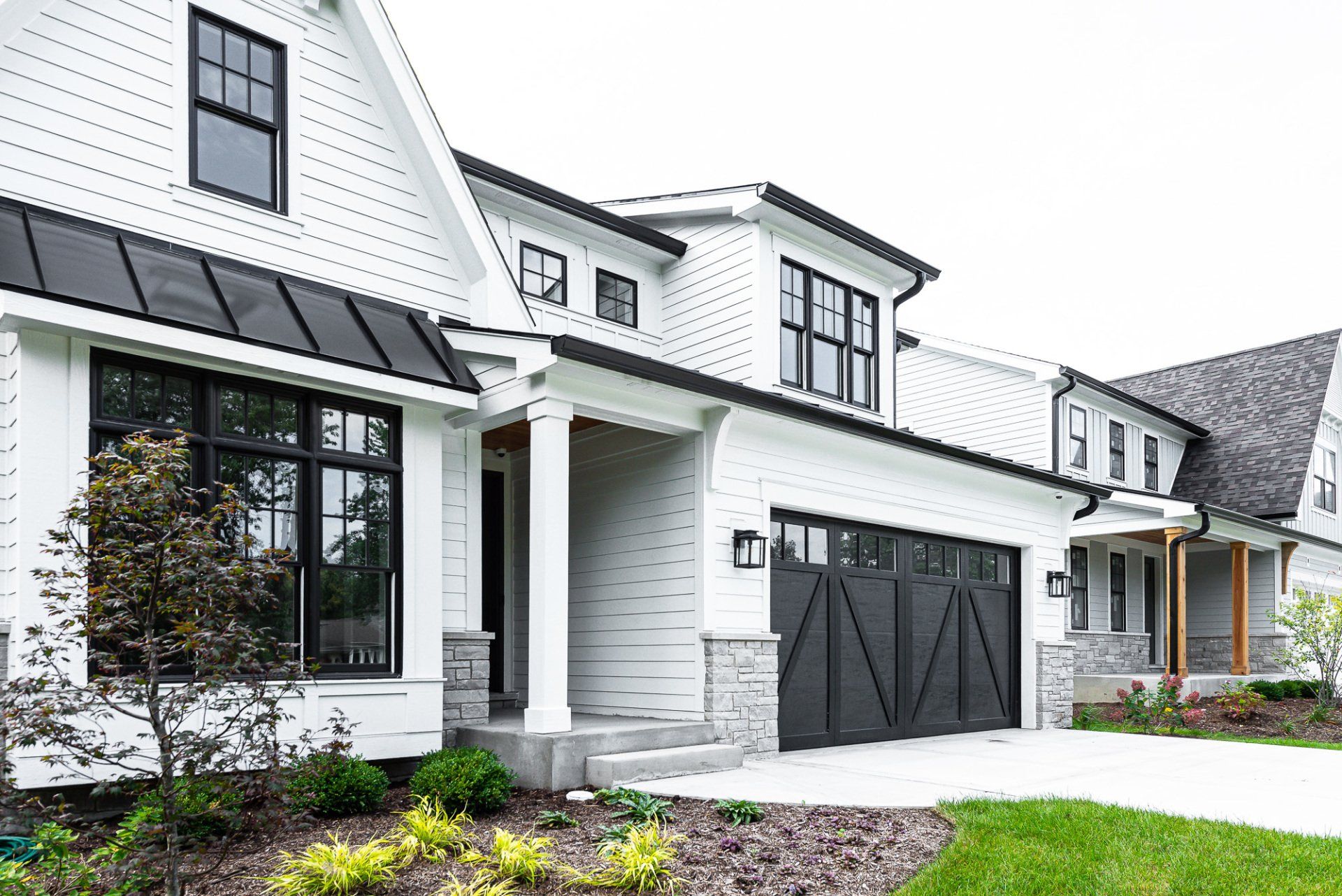A white house with black windows and a black garage door.