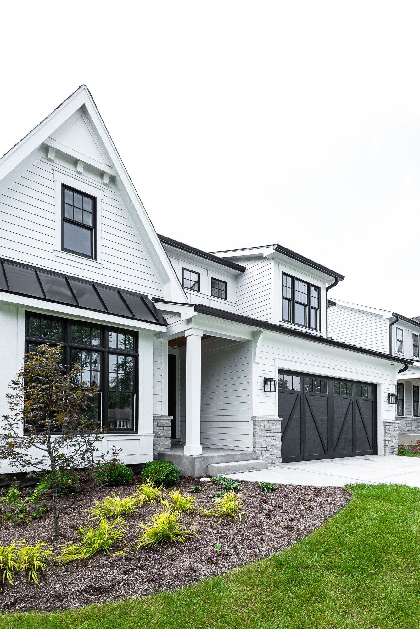 A white house with black windows and a black garage door.