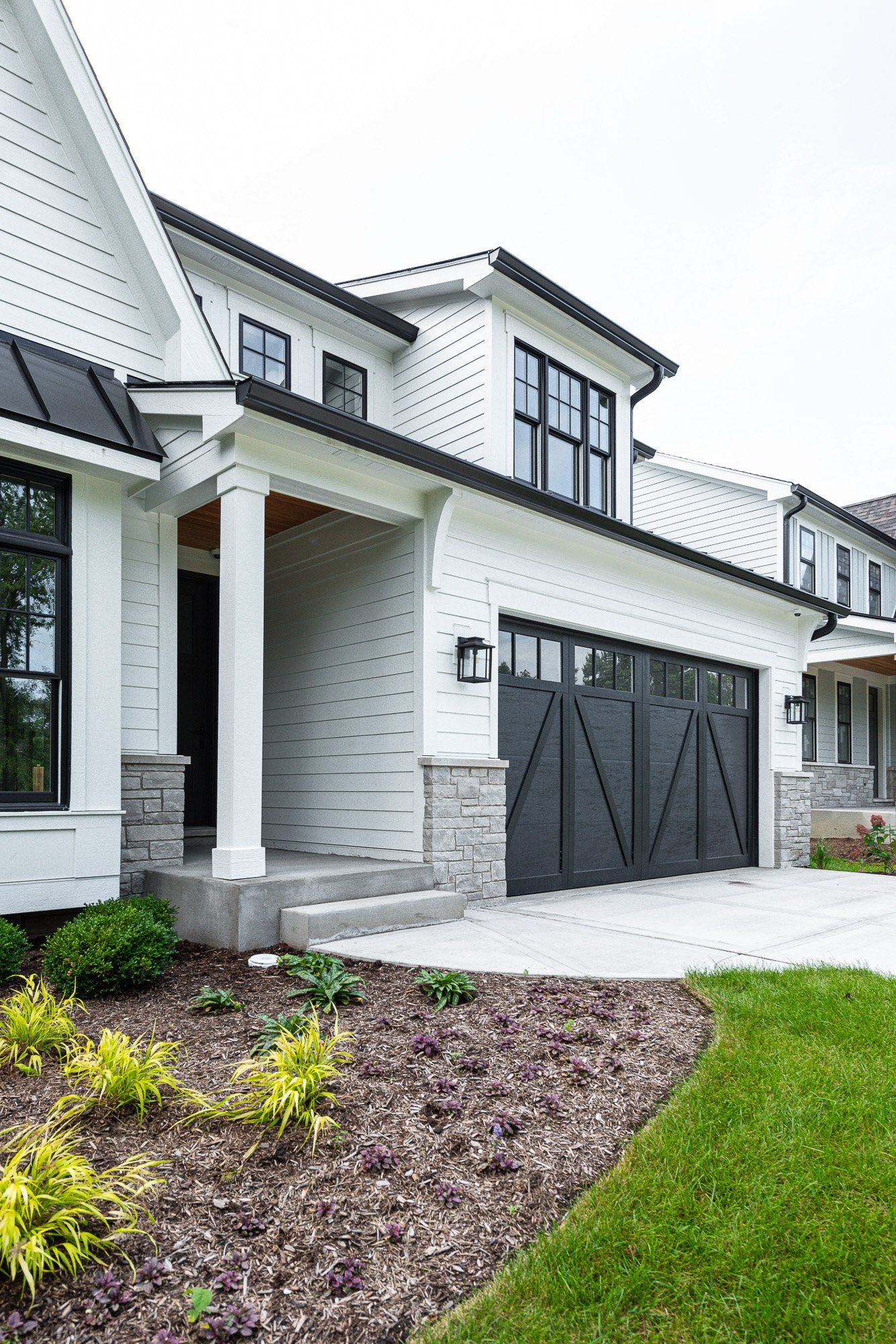 A white house with a black garage door and black windows.