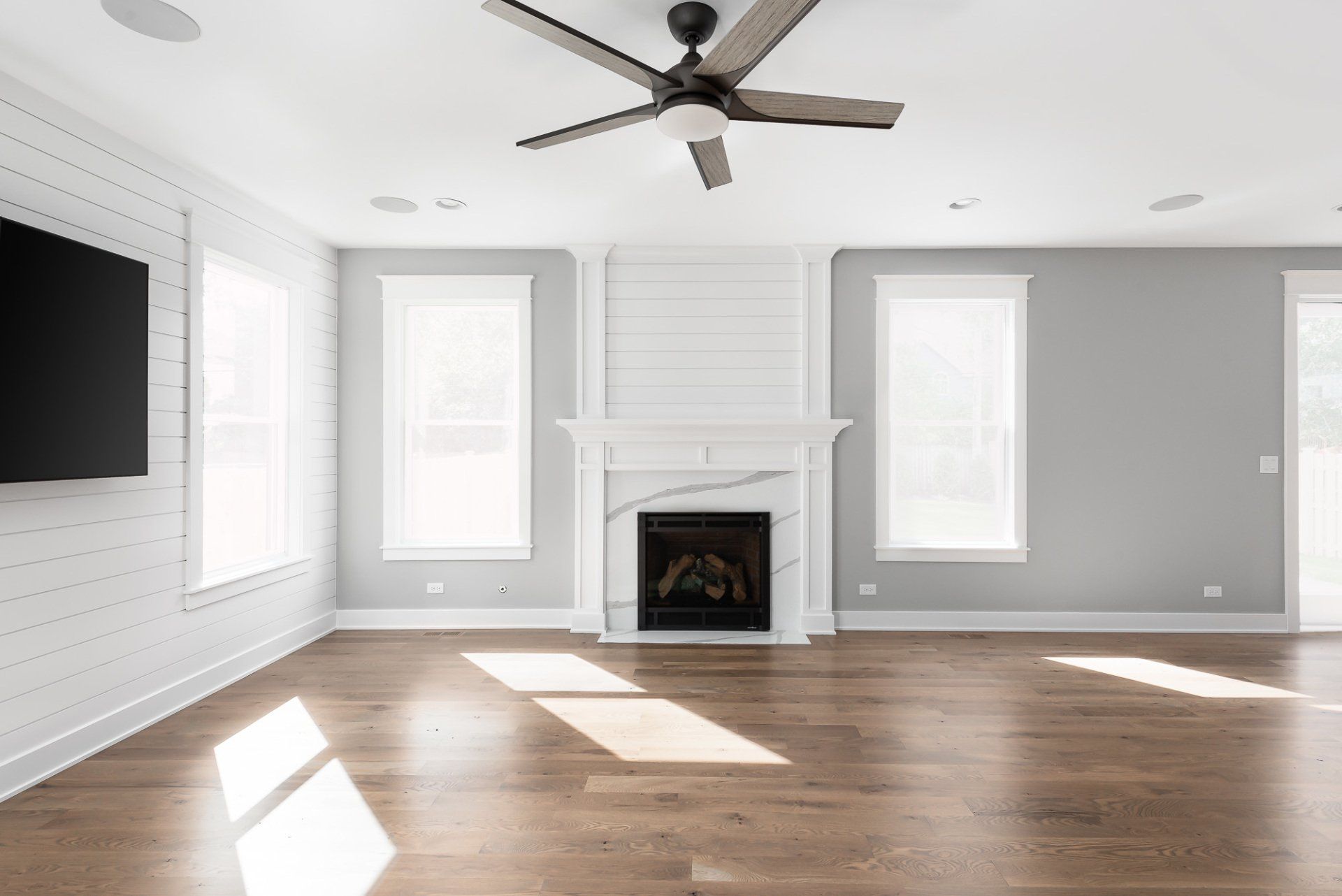 An empty living room with a fireplace , television , and ceiling fan.