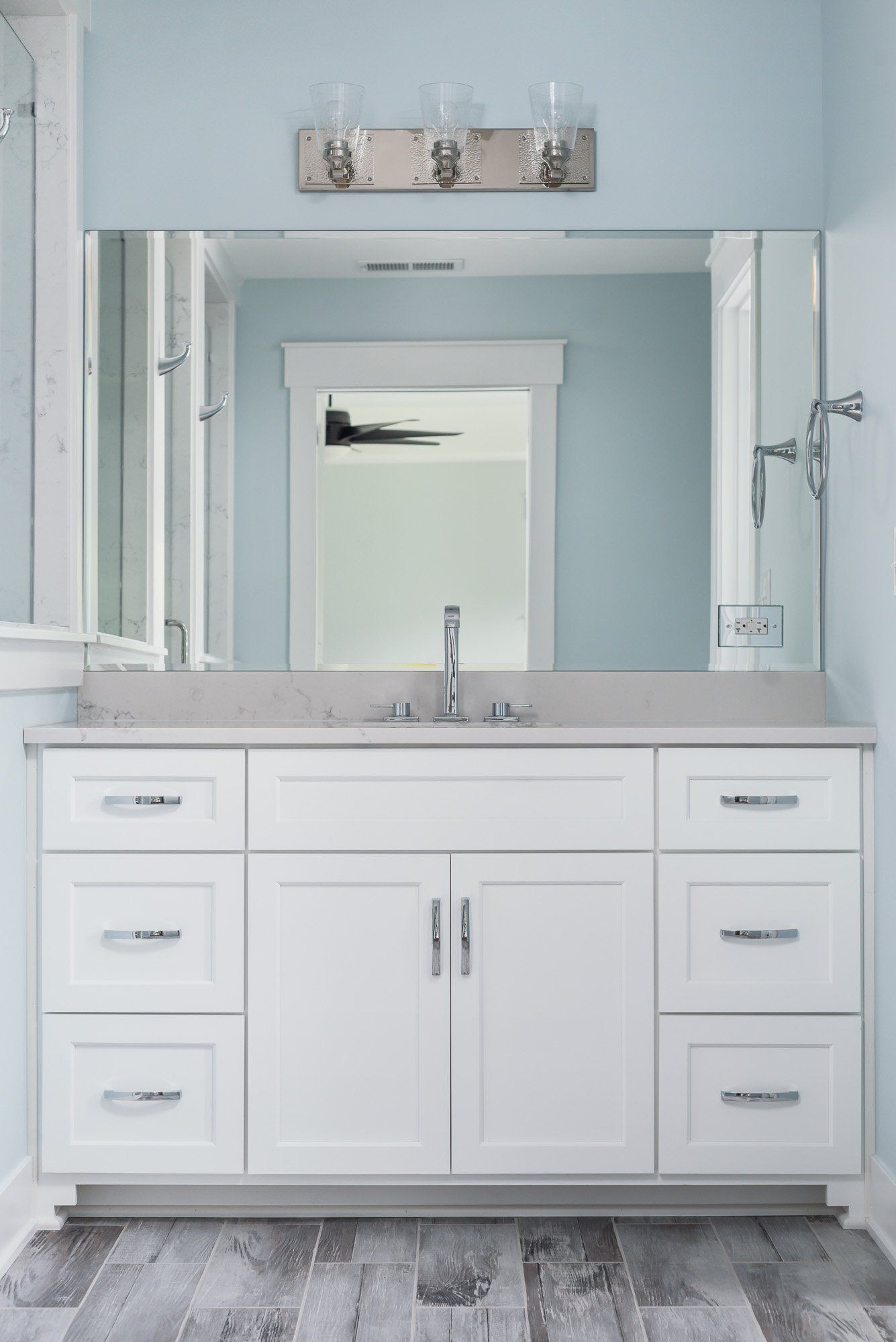 A bathroom with a sink , mirror and light fixture.