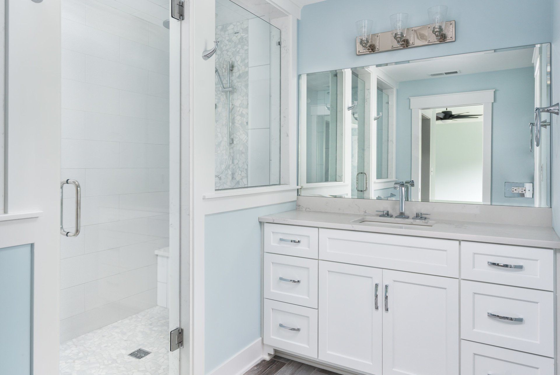 A bathroom with a sink , mirror and shower.