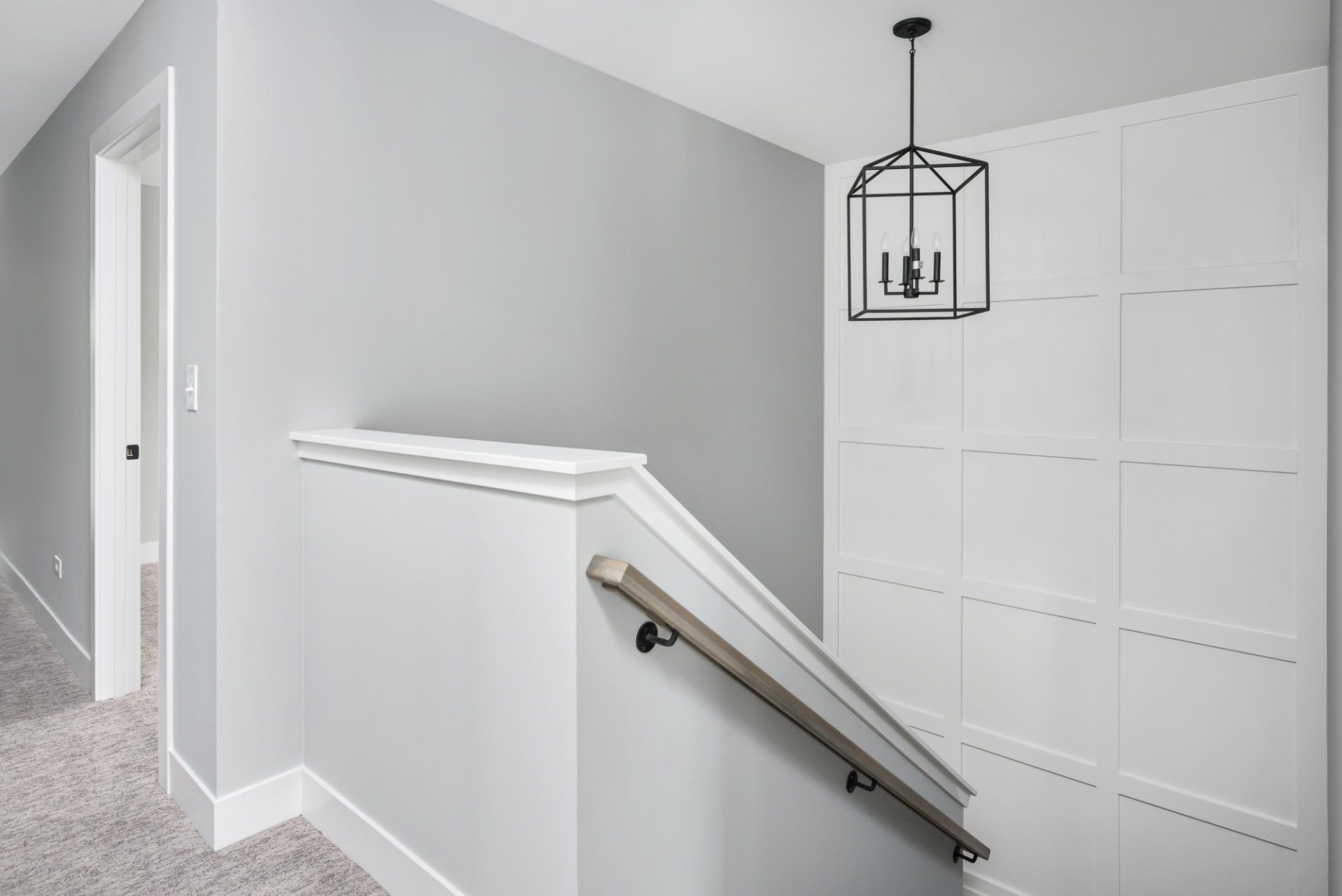 A hallway with a staircase and a chandelier hanging from the ceiling.