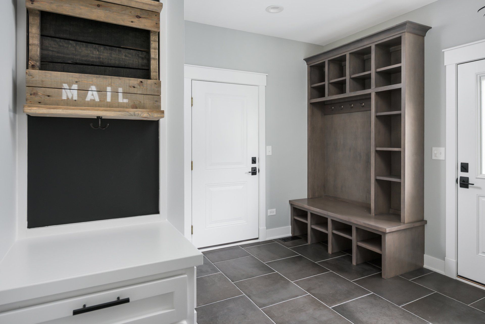 A mud room with a chalkboard and a mail holder