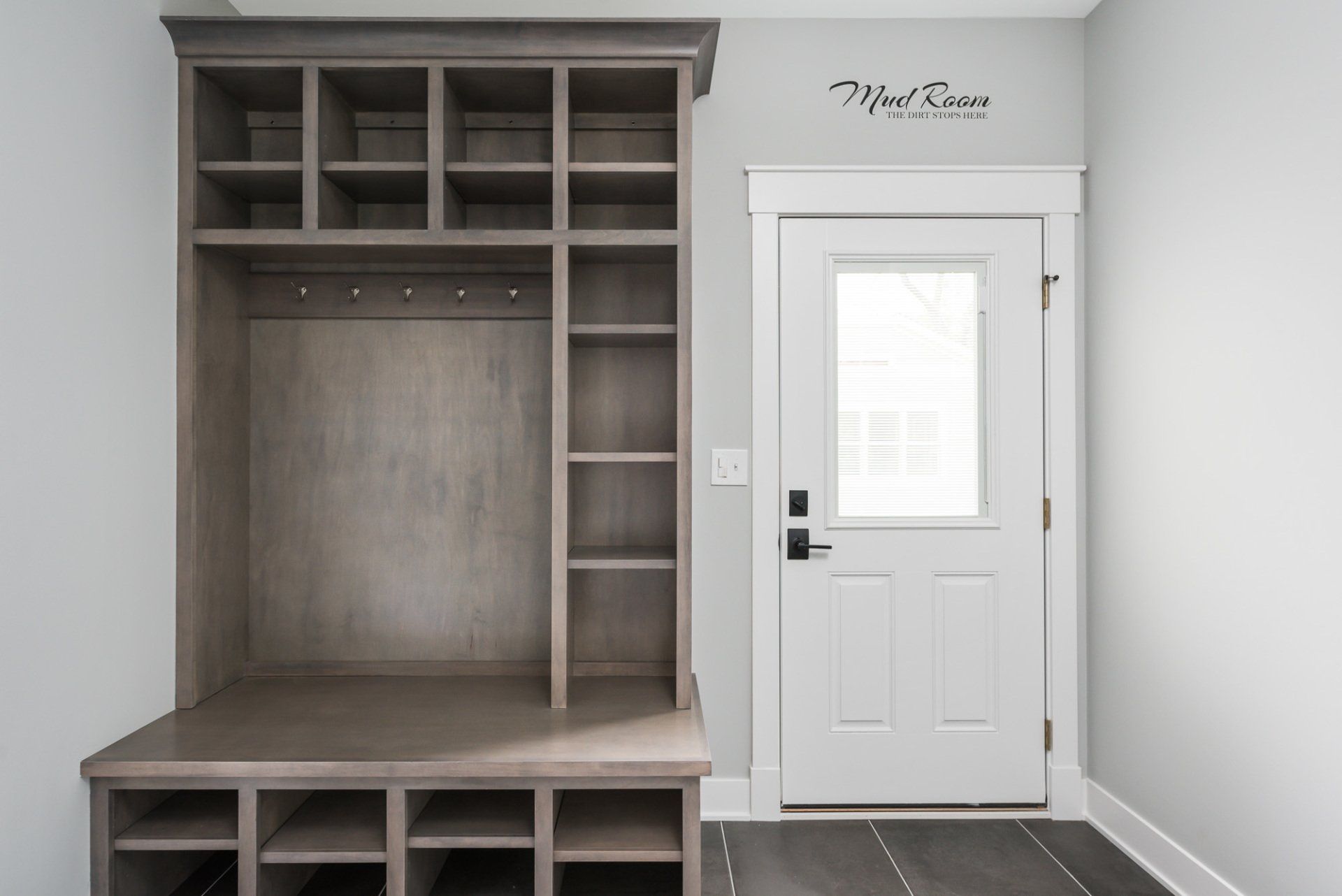 A mud room with a white door and a wooden shelf