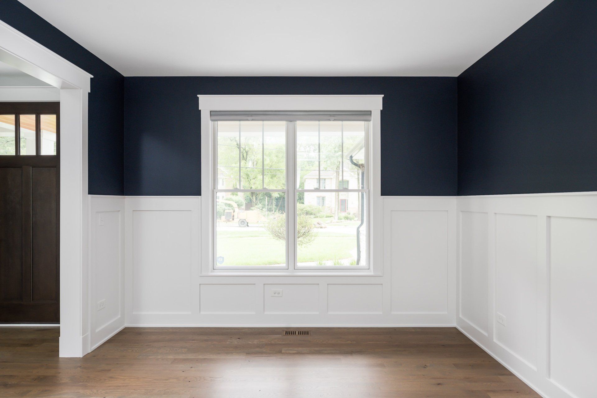 An empty room with blue walls and white trim and a window.