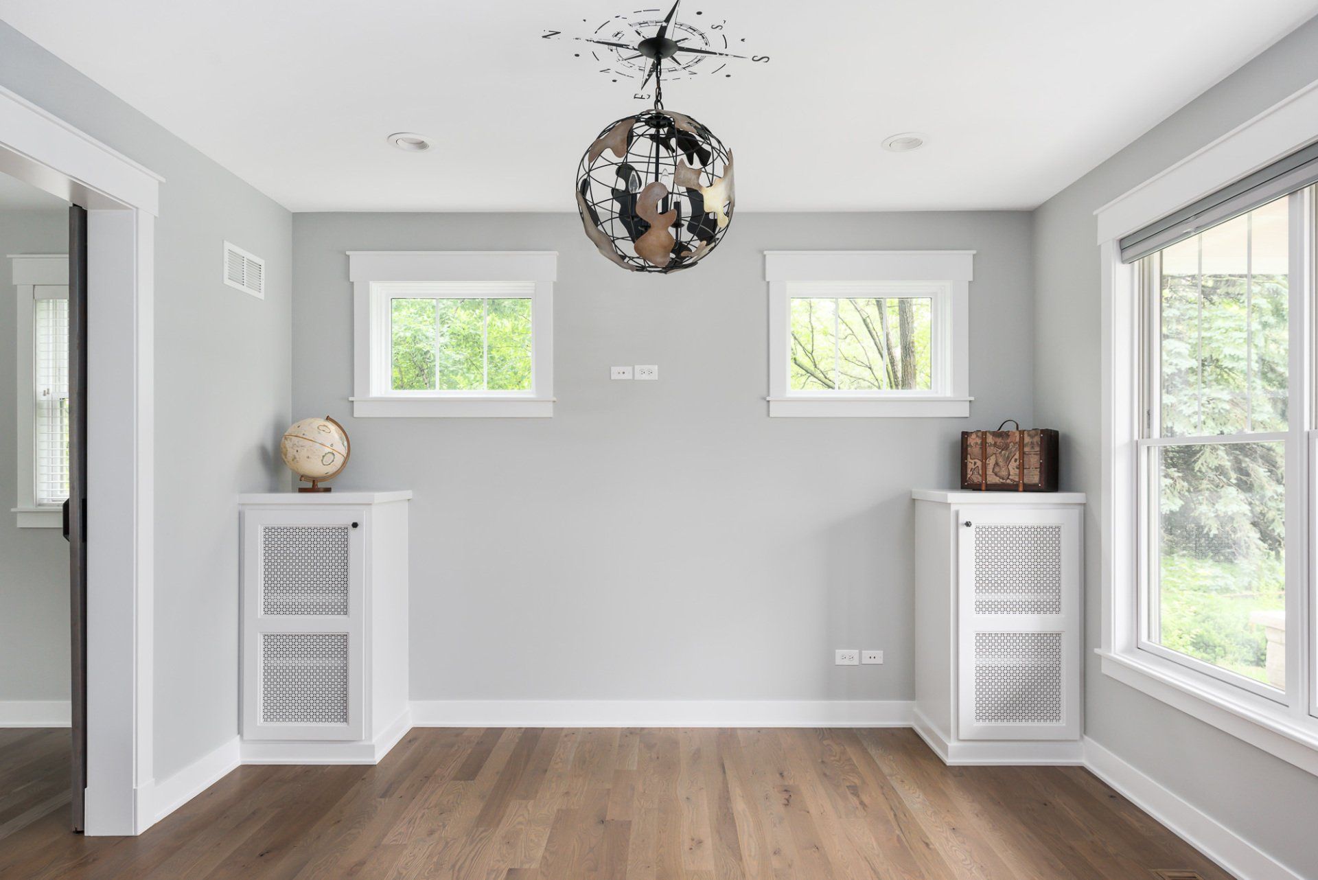 An empty room with a disco ball hanging from the ceiling and two windows.