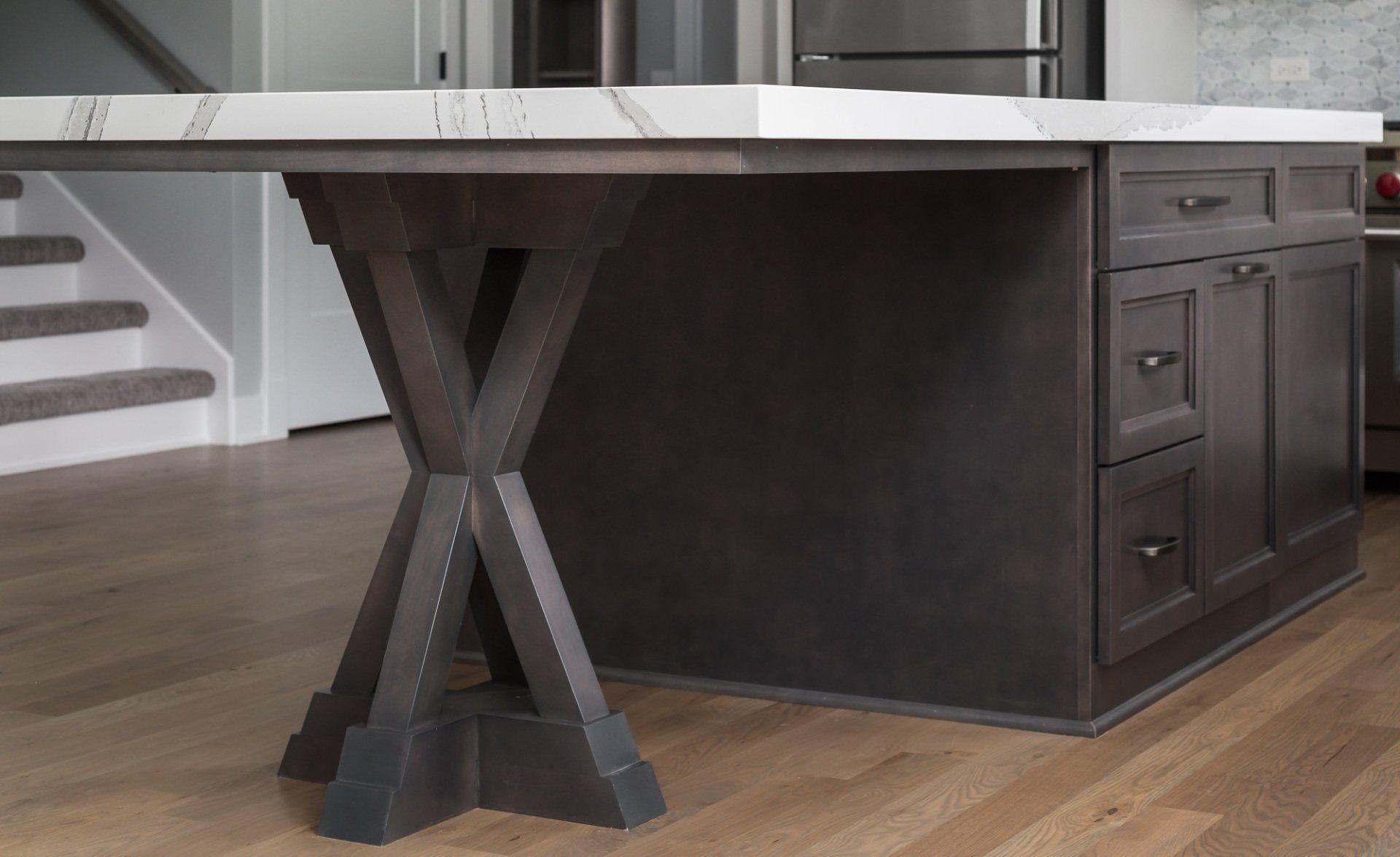 A kitchen island with a marble counter top and wooden legs