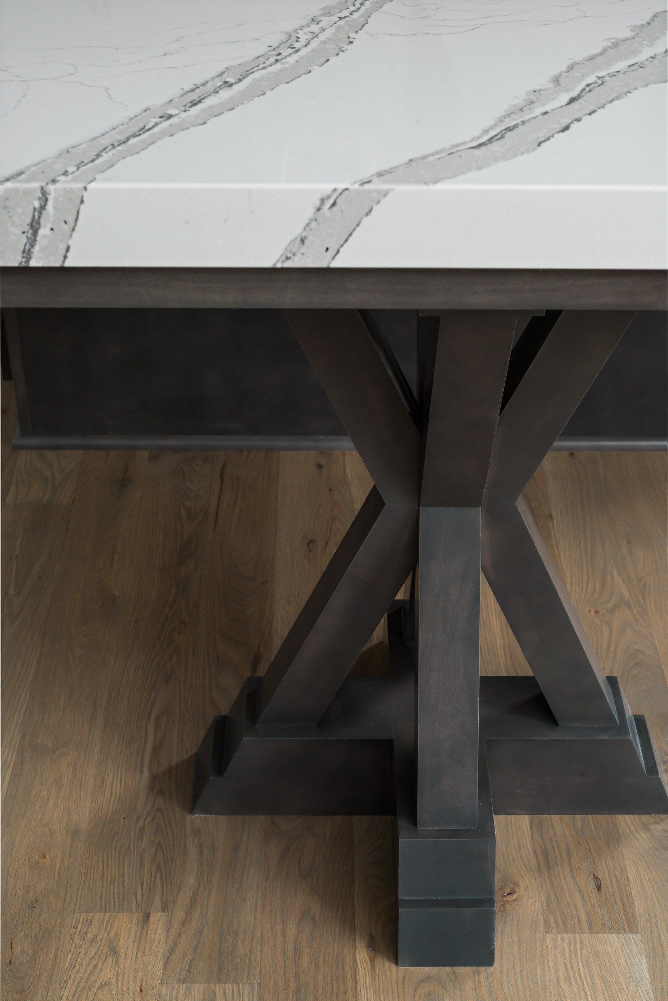 A table with a marble top and a wooden base on a wooden floor.