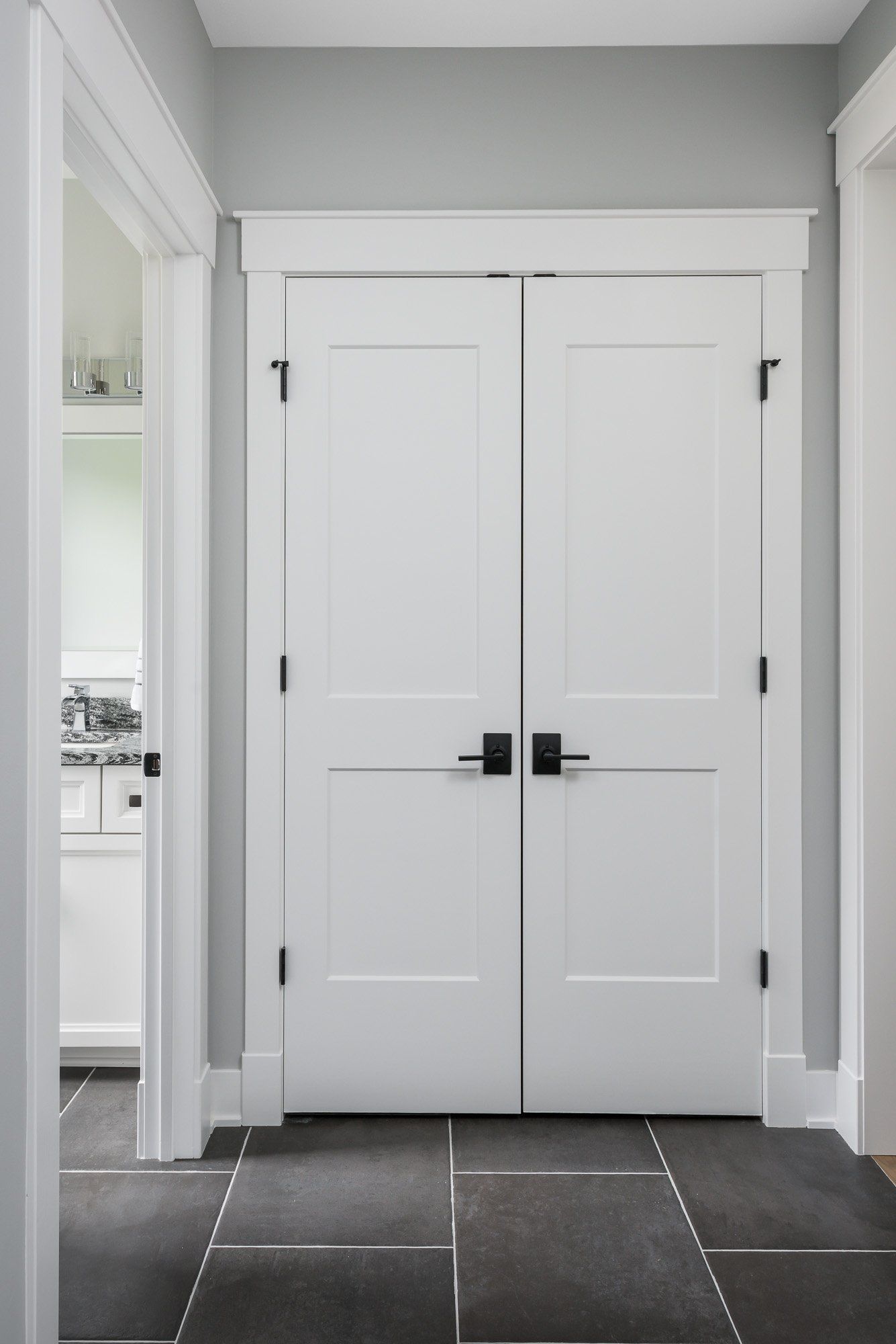 A white door with black handles is in a hallway next to a kitchen.