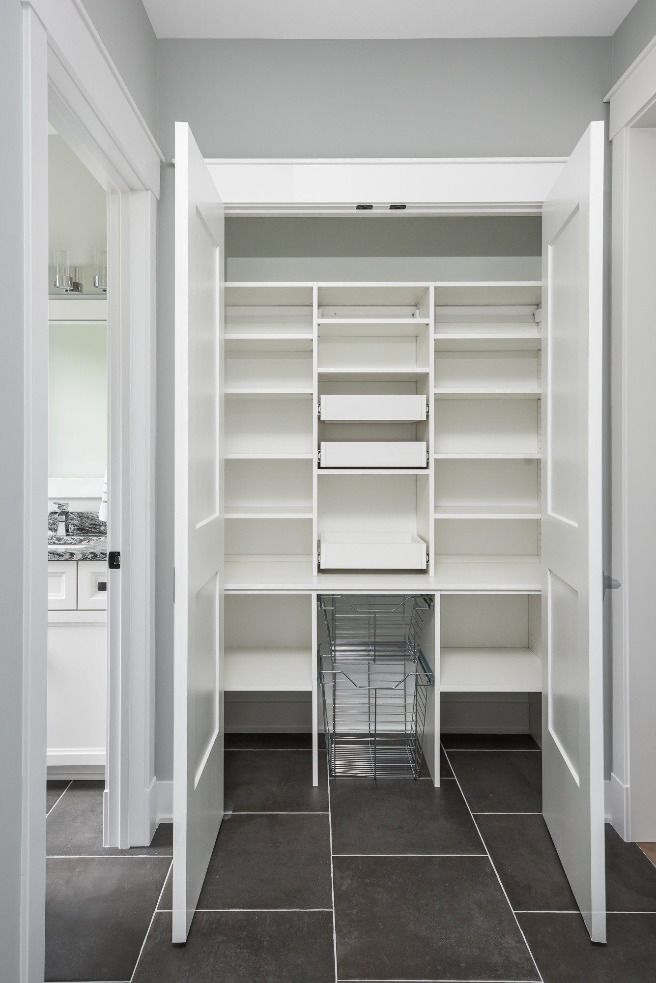 A pantry with white shelves and drawers in a house
