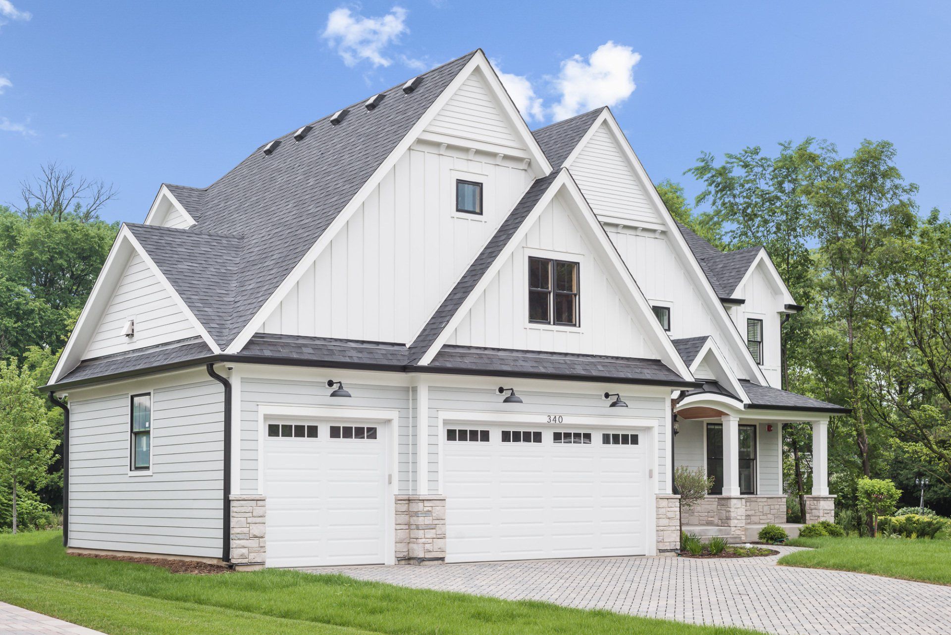 A white house with two garage doors and a gray roof.