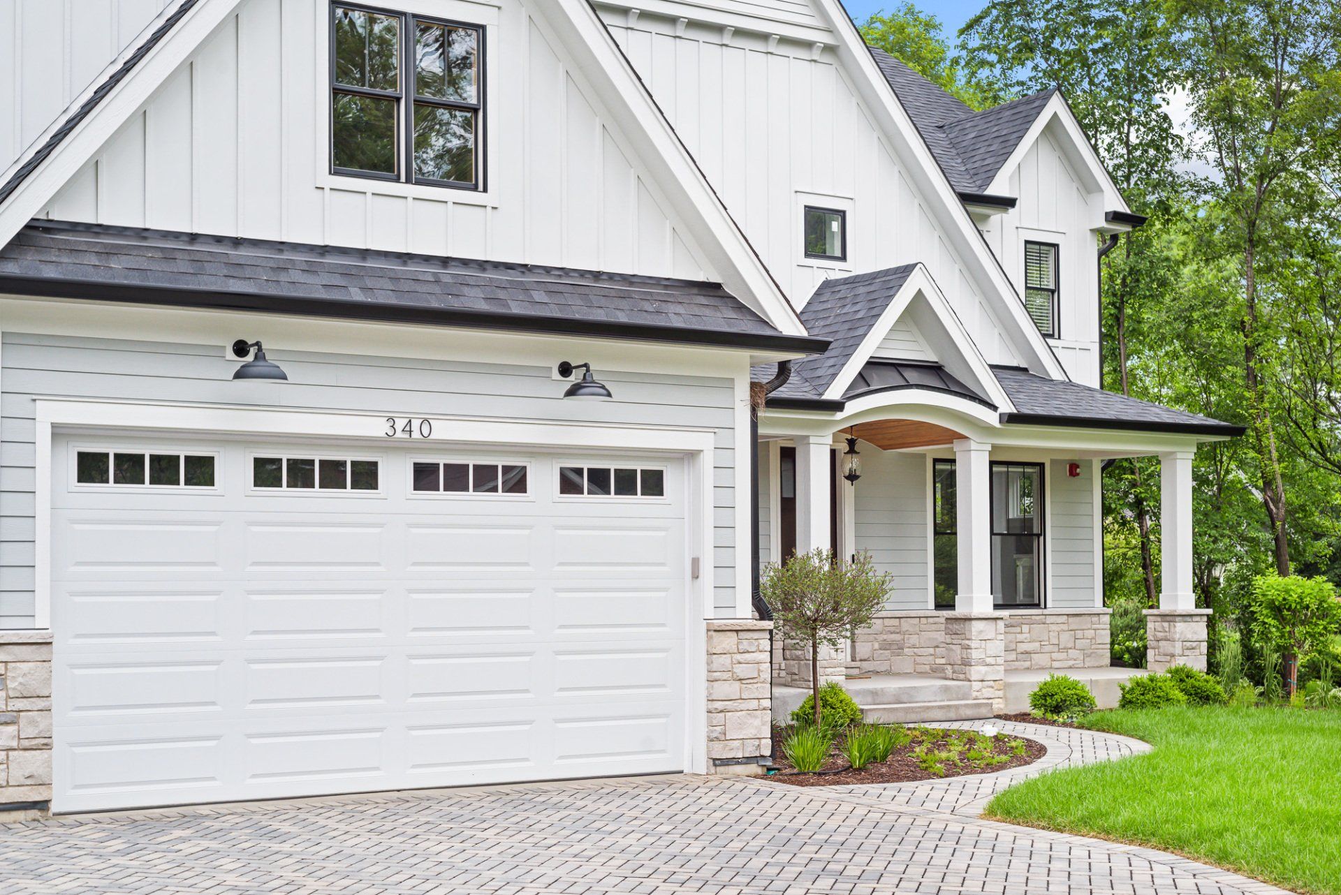 A white house with a black roof and a white garage door.